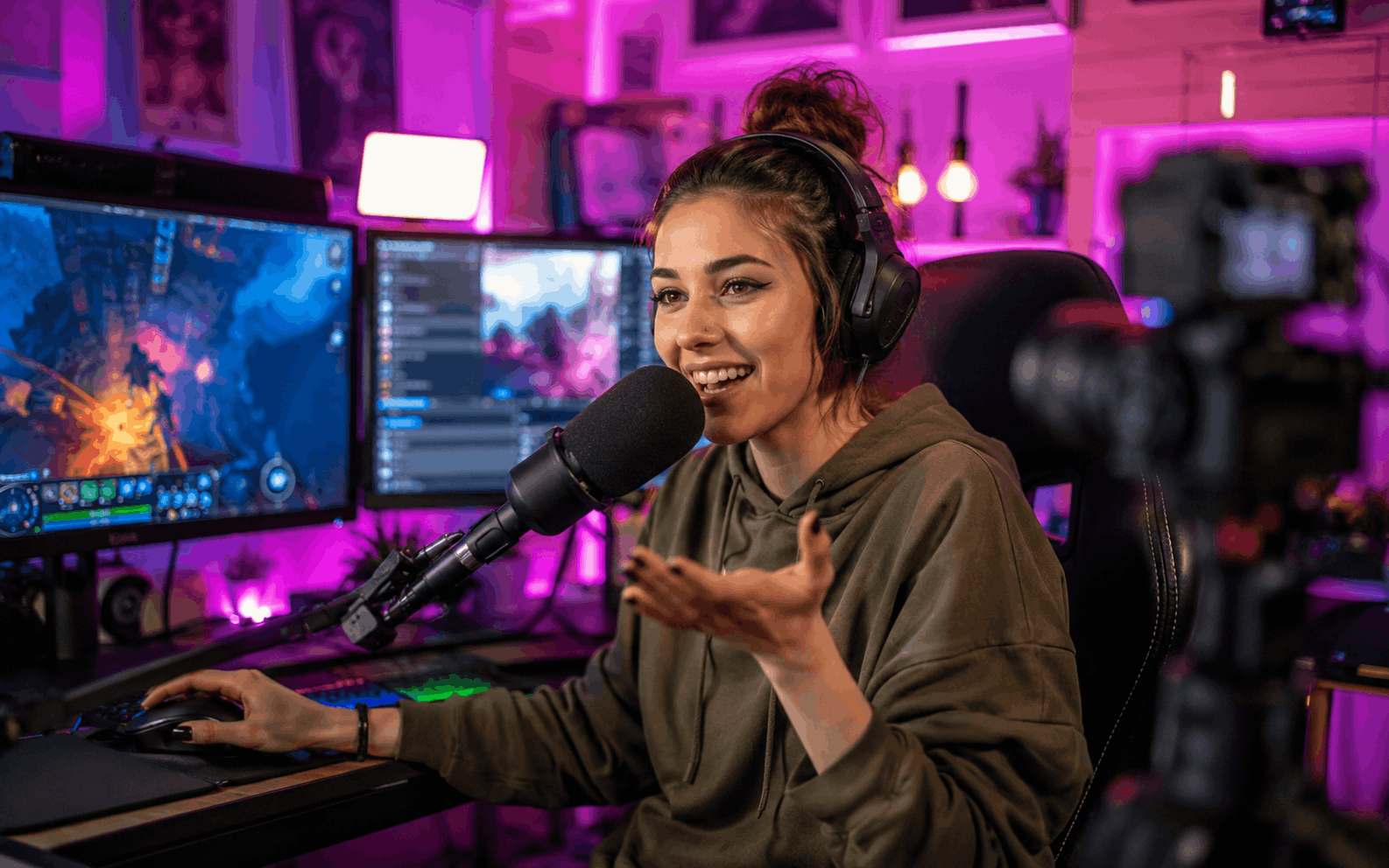 Streamer într-o cameră neon cu microfon și două monitoare